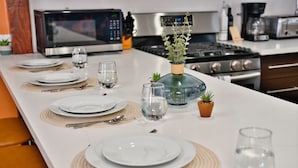 A kitchen with a long dining table set for four, equipped with plates, cutlery, and glasses. - Modern Hideaway - Hot Tub + 420 Friendly Patio - Near LAX, Beach + SoFi (Hawthorne)