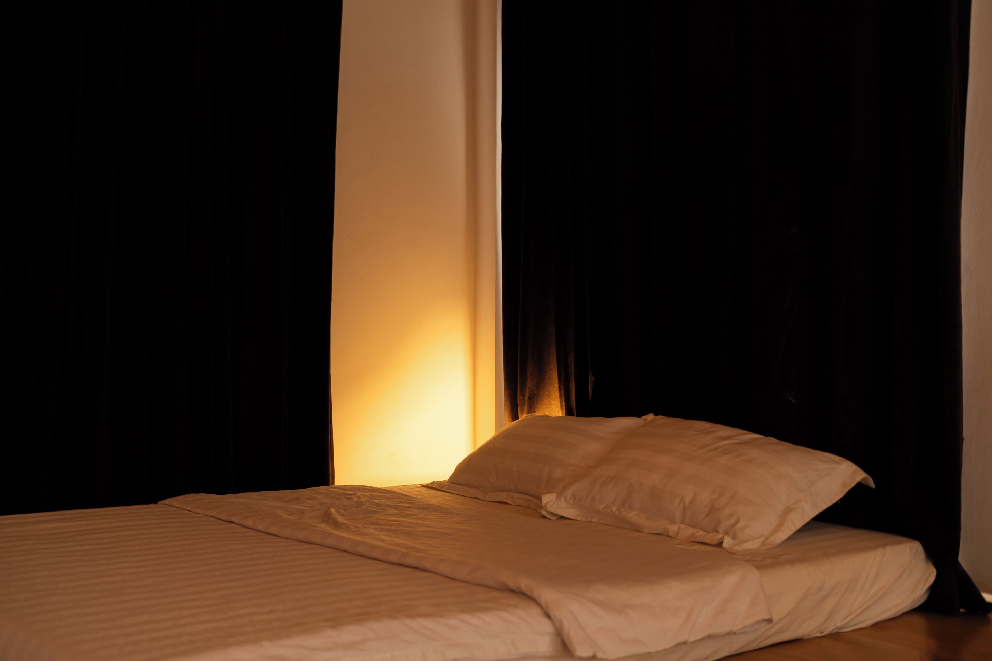 A bed with white bedding in a dimly lit room.