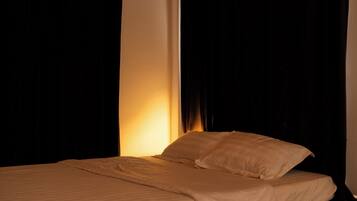 A bed with white bedding in a dimly lit room.