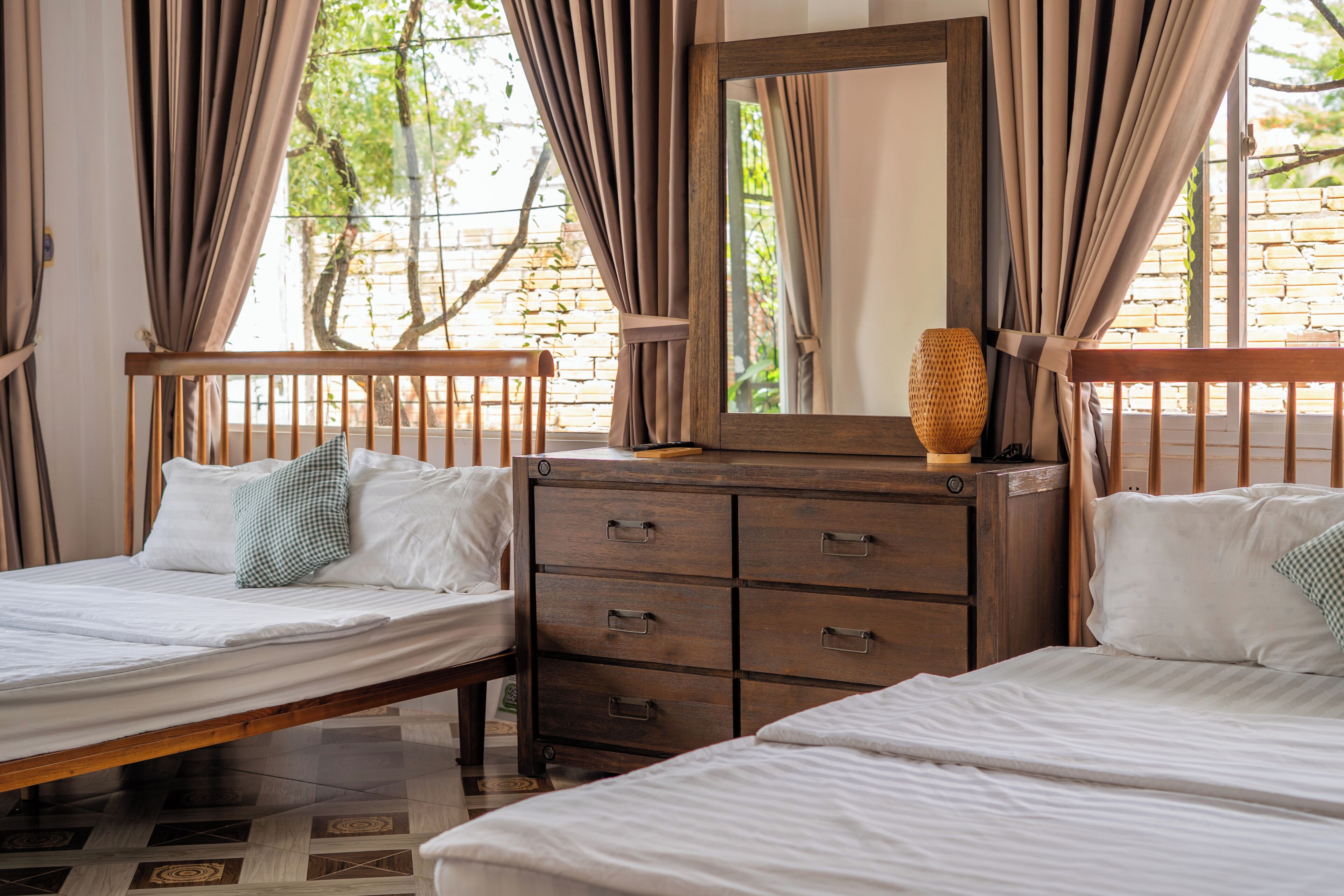 Un dormitorio con dos camas, un aparador de madera y un espejo.