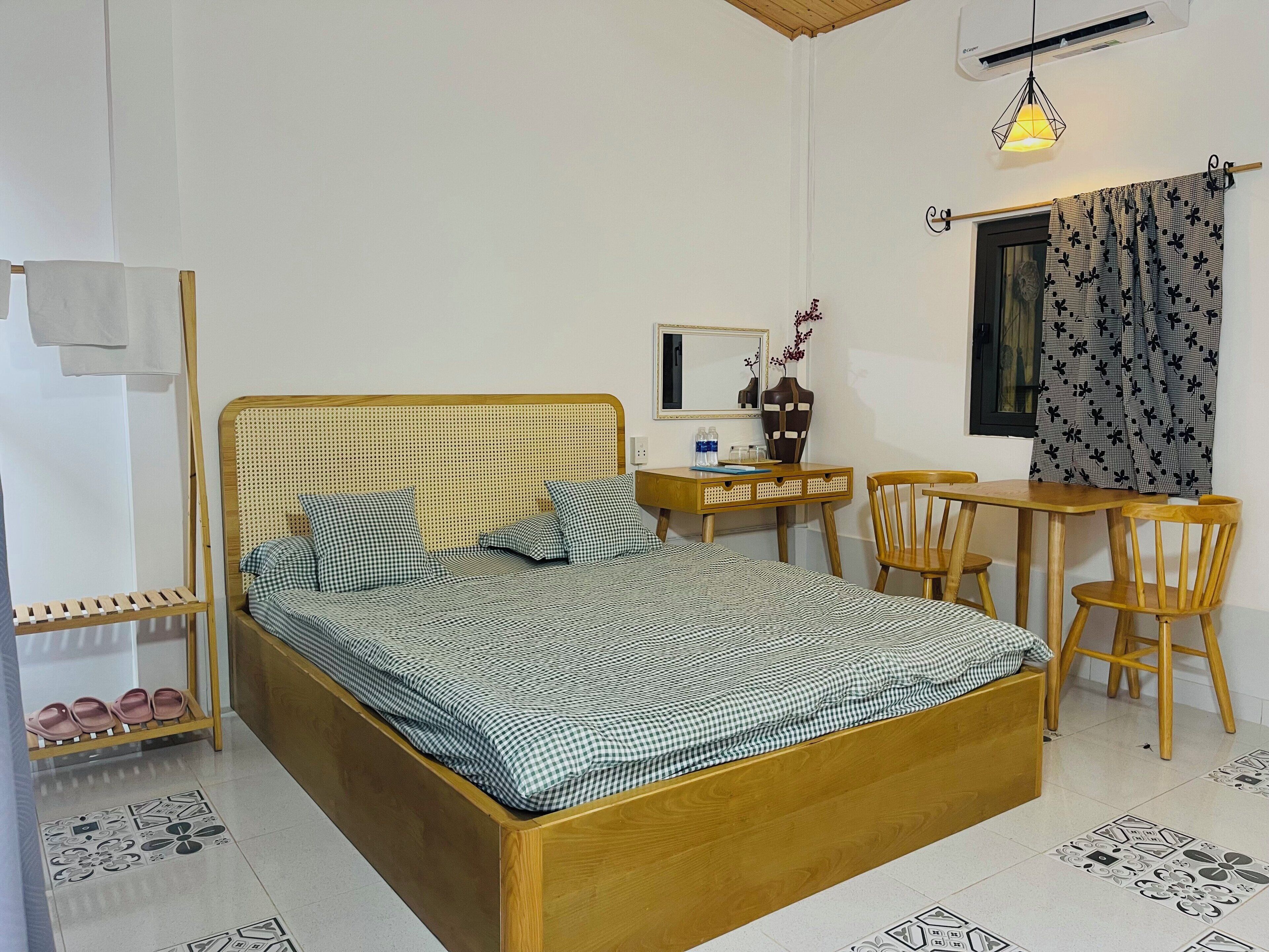 Een slaapkamer met een houten bed, een bureau, een stoel en een kleine tafel.