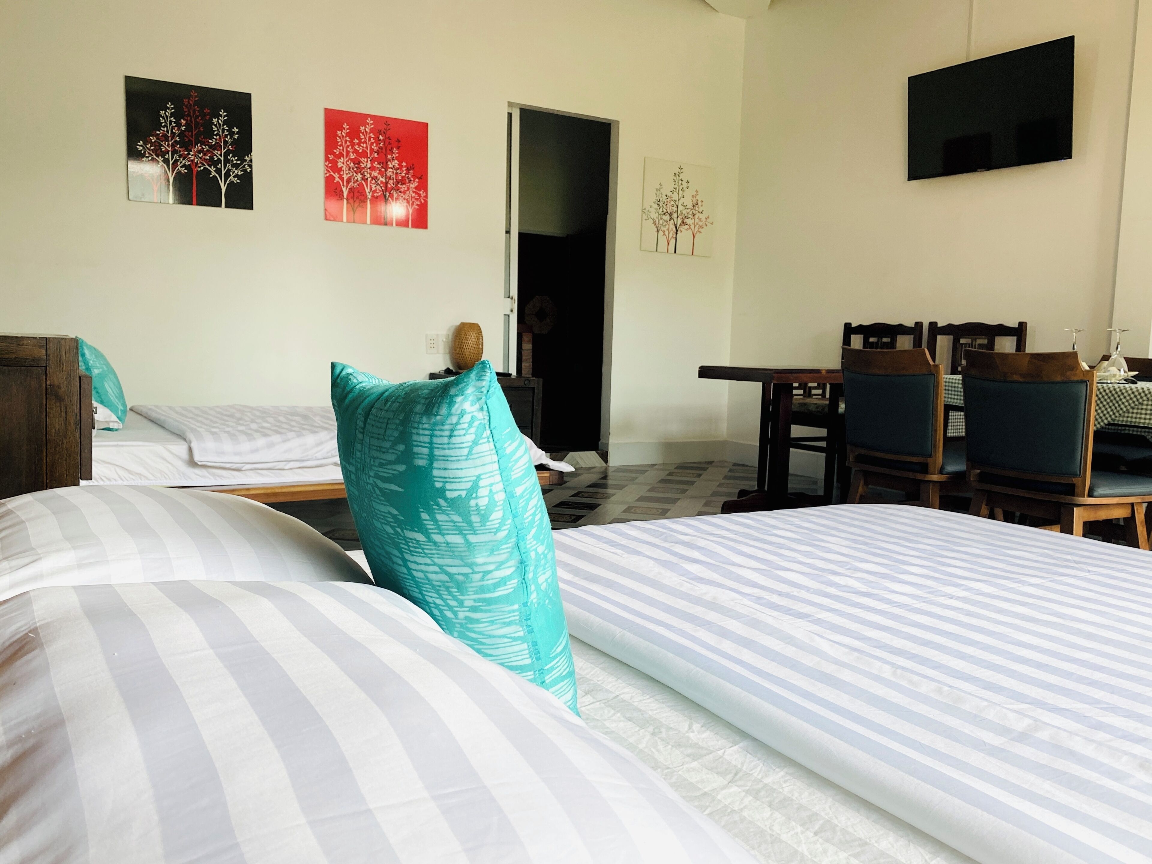 A hotel room with two beds, a dining table with chairs, and artwork on the walls.