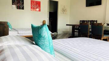 A hotel room with two beds, a dining table with chairs, and artwork on the walls.