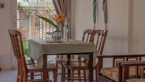 A dining table with a checkered tablecloth, surrounded by wooden chairs with cushioned seats. - Bình An Village (Phuoc Hau)