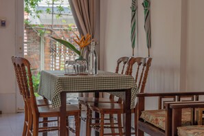 Uma mesa de jantar com toalha quadriculada, rodeada por cadeiras de madeira com assentos acolchoados.