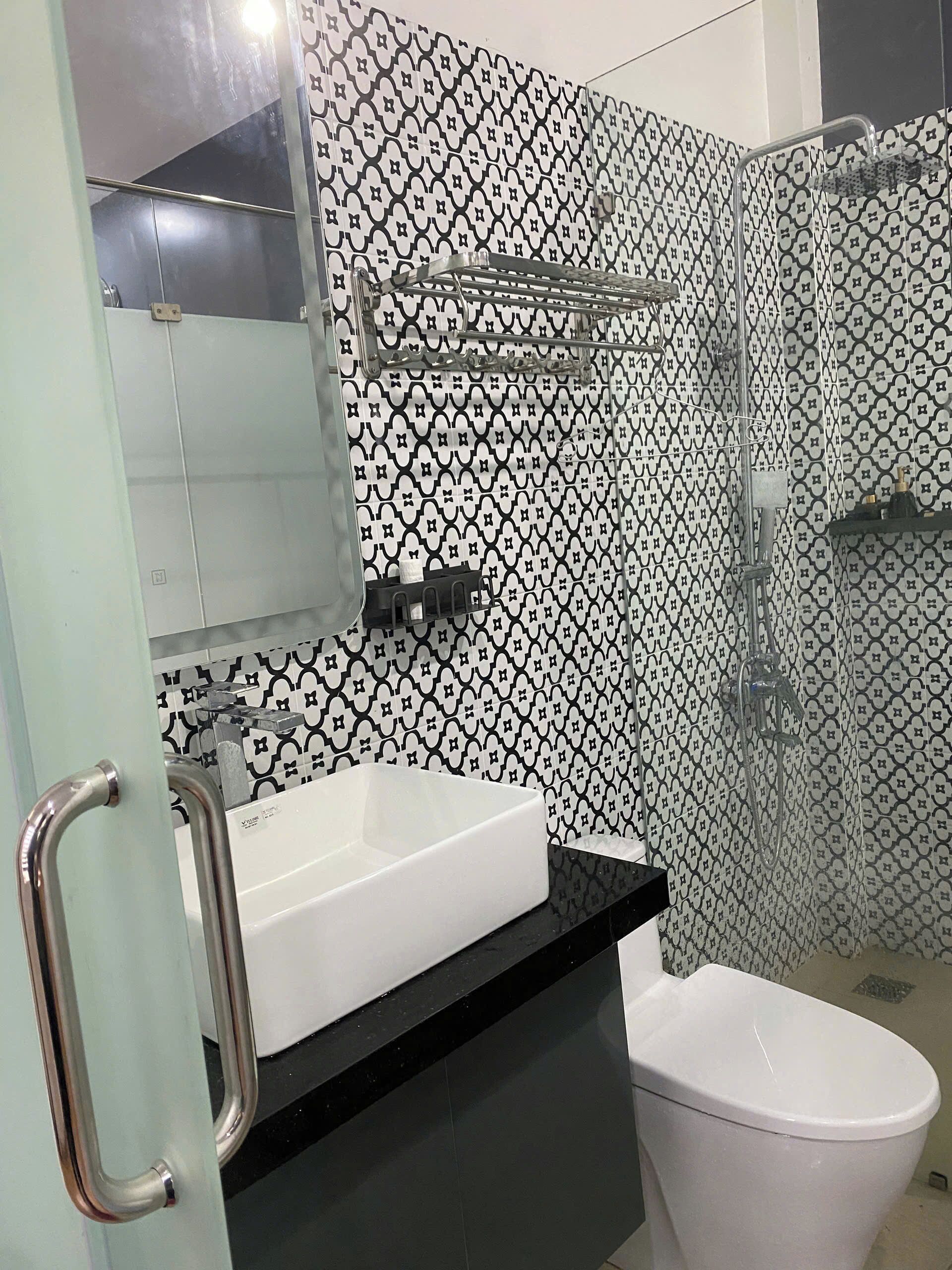 A bathroom with a white sink, black countertop, and a white toilet. There is a glass shower enclosure with a showerhead.