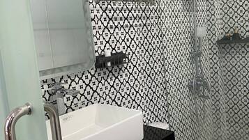 A bathroom with a white sink, black countertop, and a white toilet. There is a glass shower enclosure with a showerhead.