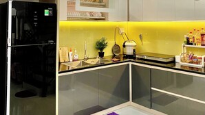 Een moderne keuken met een zwarte koelkast, een gele spatwand en een ingebouwde vaatwasser.