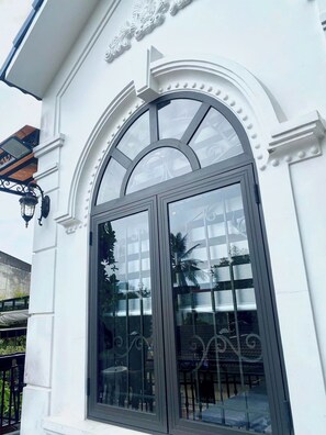 Un edificio blanco con un amplio ventanal de arco y una cornisa decorativa.