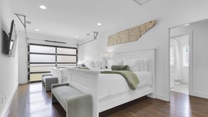 Ein modernes Schlafzimmer mit einem großen Bett, einer Sitzbank und Blick ins Freie.