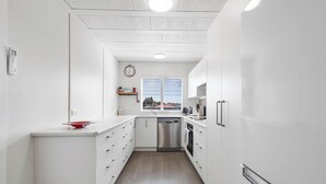 A compact kitchen with white cabinetry, a stainless steel dishwasher, and a window with blinds. - Bunker 2 "Urban meets Rustic" (Te Awamutu)