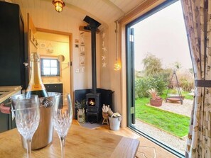 Een gezellige woonkamer met een open haard, een groot raam en een fles champagne op de tafel.