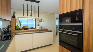 A modern kitchen with a central island, built-in oven, microwave, and a view to the outside.