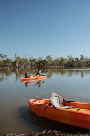 Two kayaks on calm water with trees in the background.