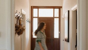 A hallway with a wooden floor, a door at the end, and a wall-mounted decoration. - The River Block (Bookpurnong)