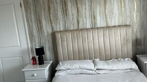 Une chambre à coucher comprenant un lit, une table de chevet, une lampe et une commode.