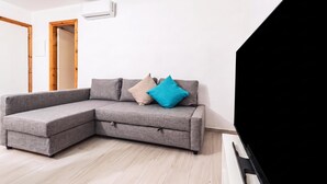 Un salon moderne avec un canapé d’angle, un téléviseur à écran plat et une porte en bois.