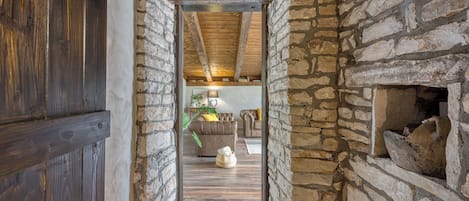Un couloir étroit aux murs de pierre, avec une porte en bois et des poutres apparentes au plafond.