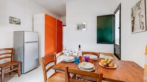 A compact living space with a dining area, a refrigerator, and a door with a green panel.