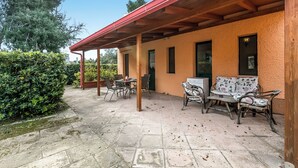 An outdoor patio with stone flooring, wooden pergola, and wicker furniture.