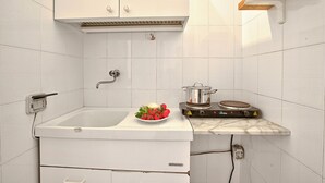 Une cuisine avec des meubles blancs, un évier et une cuisinière.