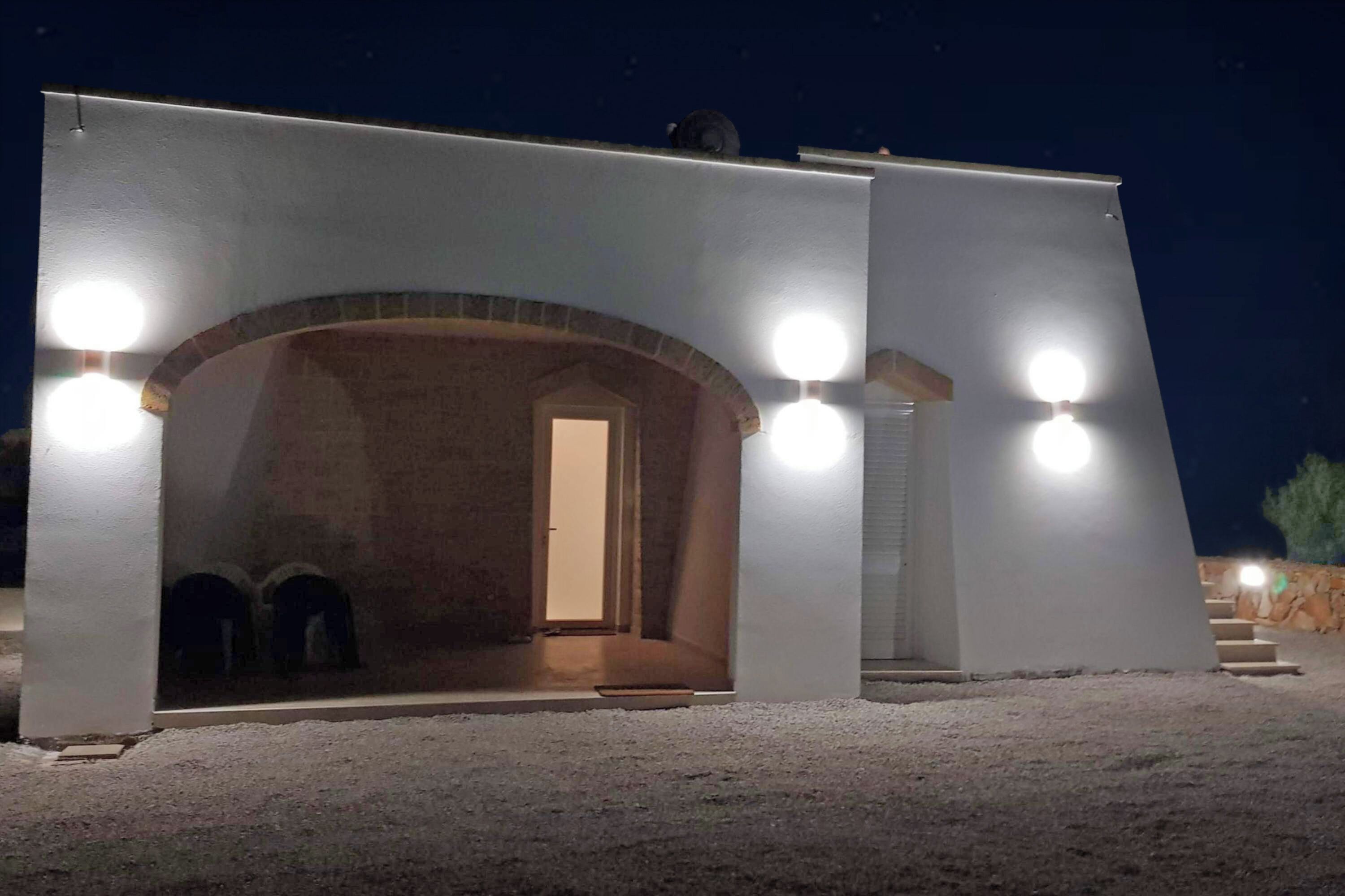 A building with a large arched entrance, a door, and three round lights on the exterior.