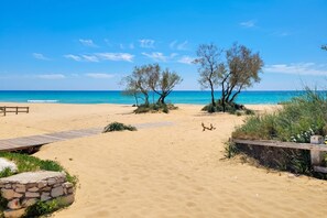 A beach with a wooden walkway, a stone structure, and trees. - Villa Pescoluse with Pool and Sea View, Salve, Italy (Salve)