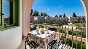 A balcony with a table set for dining, chairs, and a view of neighboring buildings. - Borgo Primizia M4 Pool And Sea, Otranto, Italy (Otranto)