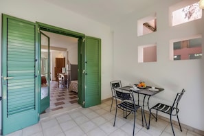 A room with a dining table and chairs, a green door, and a view of another room. - Borgo Primizia M2 Pool And Sea, Otranto, Italy (Otranto)