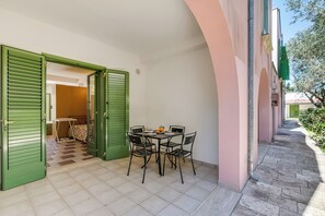 Un patio con una mesa, sillas, una puerta verde y suelo de baldosas.