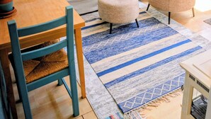A living room with a sofa, ottoman, and a wooden table. A blue staircase with a basket on the landing is visible. - Chic 4 rm 1 bed retreat, No Berkeley area, WiFi, private deck, near UC, nature, (Kensington)