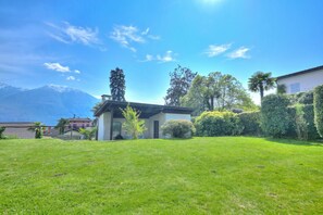 A house with a well-maintained lawn, a mountain in the background, and a clear sky.