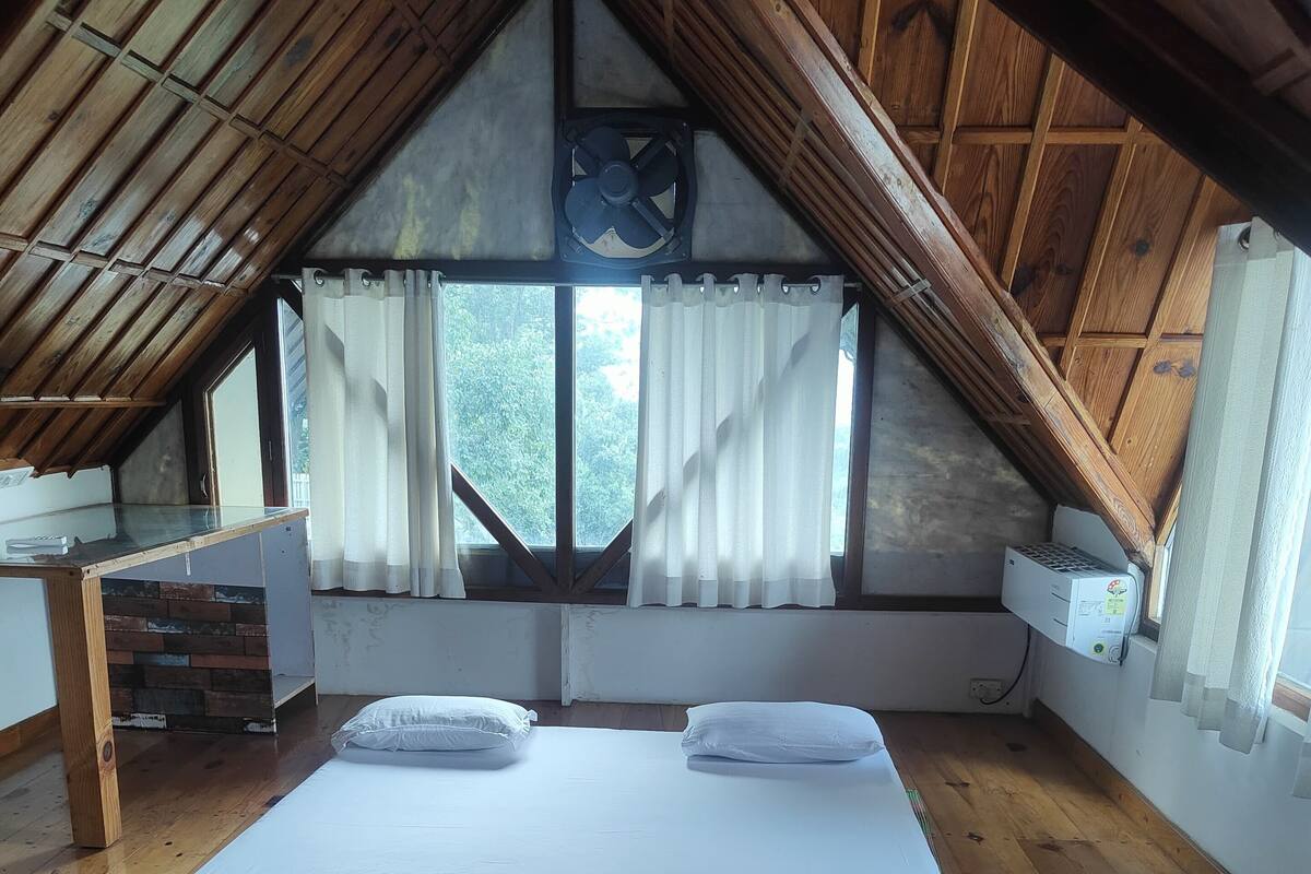 Een slaapkamer met een houten plafond, een bed, een nachtkastje en een raam met gordijnen.