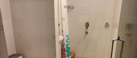 A bathroom with a toilet, shower, and a glass-enclosed shower area.