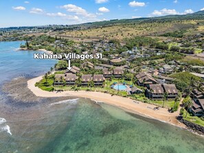 Ein Luftbild von Kahana Villages 31, mit Strandvillen, Swimmingpools, einem Strand und freiem Blick auf den Ozean.
