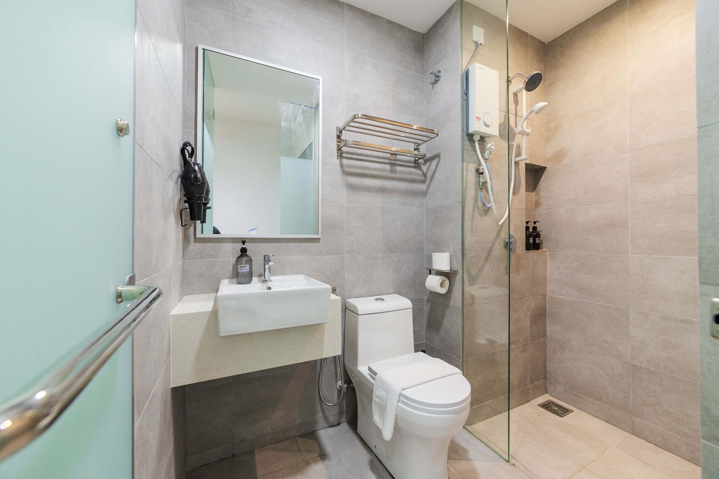 A modern bathroom with a glass shower enclosure, a white sink, and a toilet.