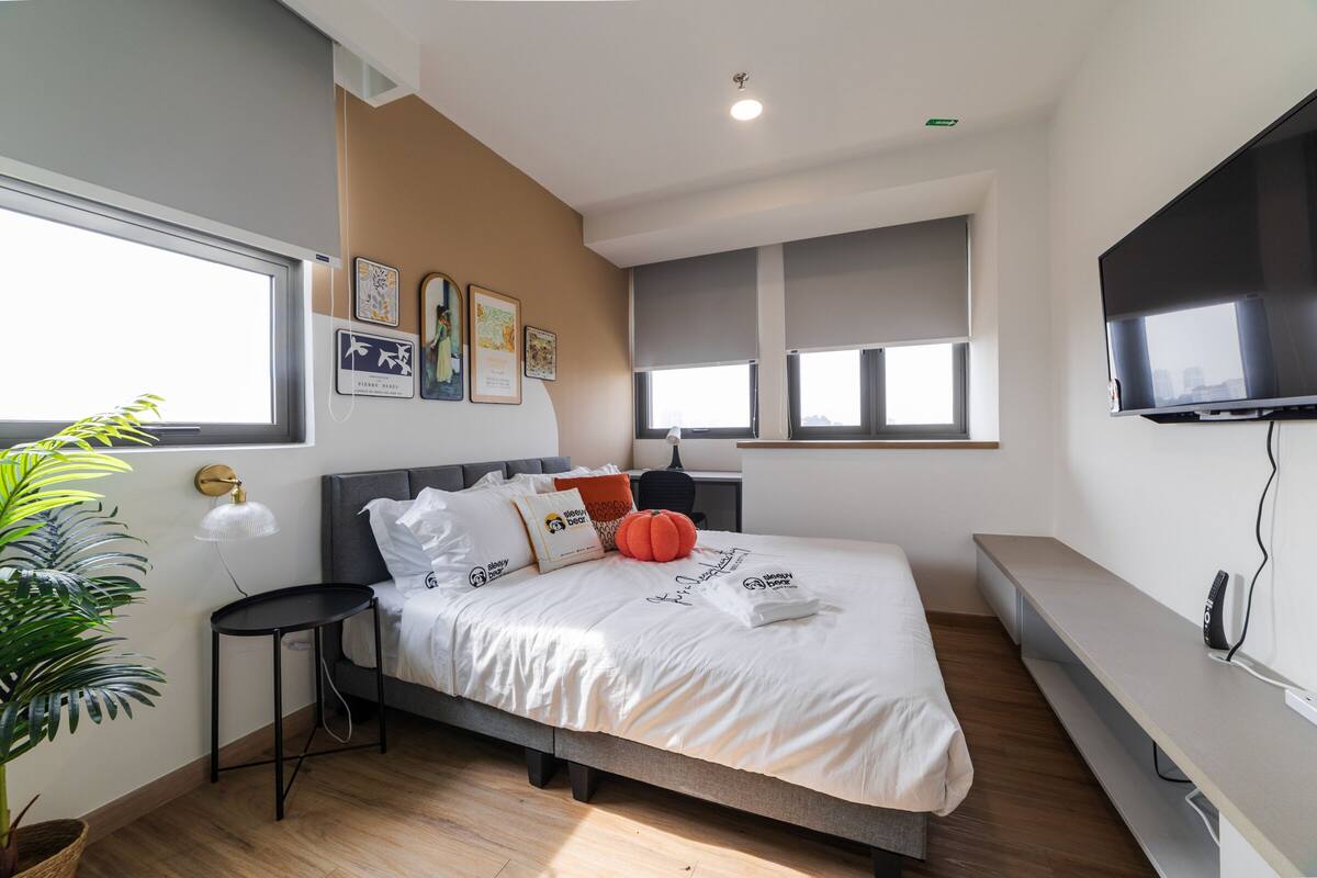 Ein modernes Schlafzimmer mit Bett, Nachttischen, einem Fernseher und einem großen Fenster.