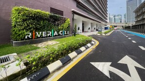 A modern building with a sign reading "Rivercity" and a clear road with directional arrows. - Riveria City KL Sentral by Sleepy Bear (Kuala Lumpur)