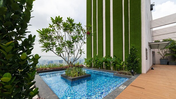 A rooftop pool with a mosaic tile design, surrounded by greenery and a wooden deck. - Riveria City KL Sentral by Sleepy Bear (Kuala Lumpur)