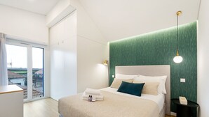 Un dormitorio moderno con una cama grande, una pared de acento verde y vistas a través de una puerta corredera.