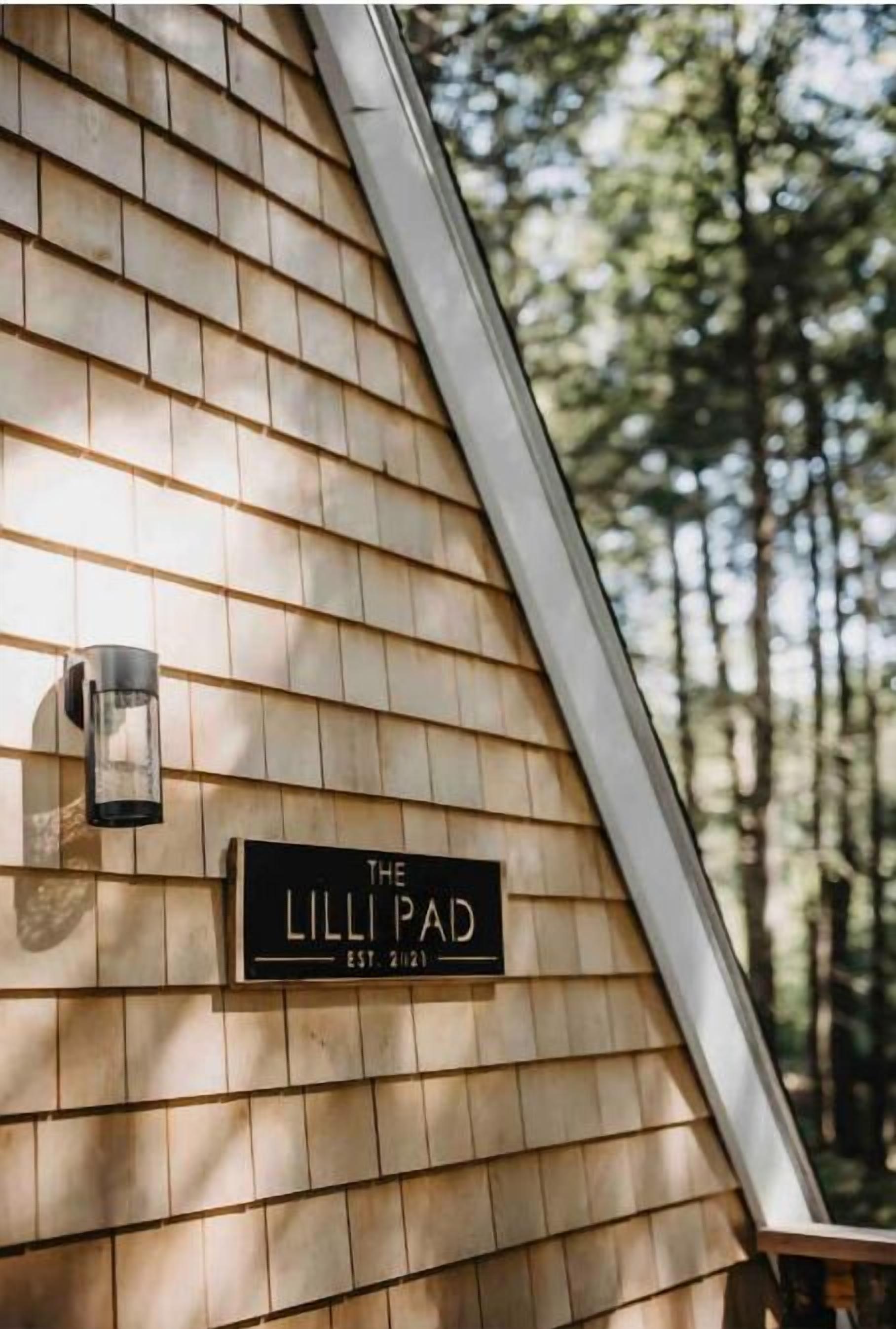 A wooden shingle wall with a sign reading "The Lilli Pad" and a black lantern-style light fixture.
