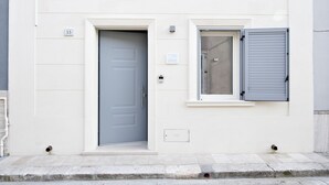 A building facade with a grey door and a window with grey shutters.