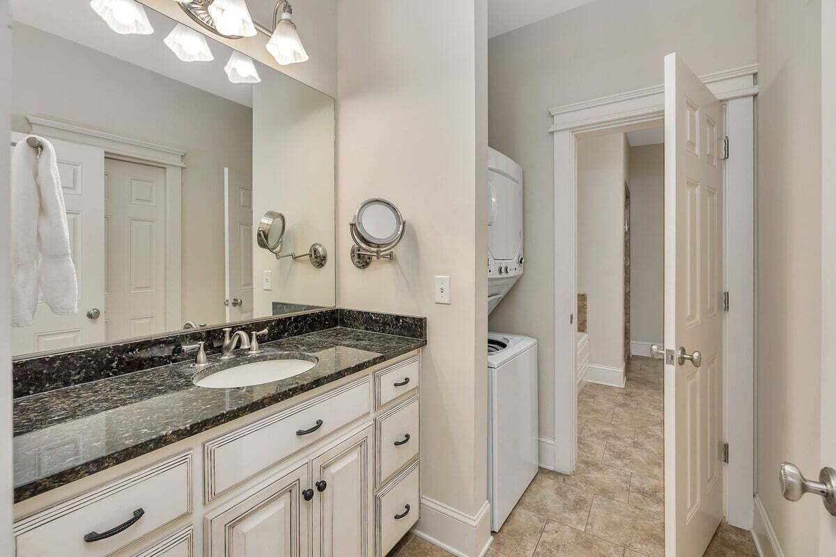 A bathroom with a double sink vanity, a large mirror, and a walk-in shower.