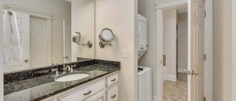 A bathroom with a double sink vanity, a large mirror, and a walk-in shower.