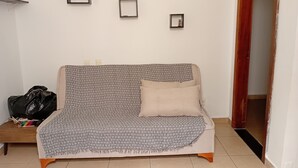 Ein Zimmer mit einer Couch, einem kleinen Tisch und einer Tür.