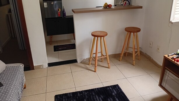 Eine kompakte Küche mit einem schwarzen Kühlschrank, Holzstühlen und einer kleinen Arbeitsplatte.