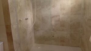 Eine Dusche mit Glastür und Handbrause.