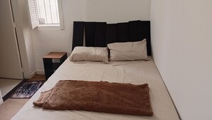 Ein Schlafzimmer mit einem Bett, einem Nachttisch und einem Fenster.