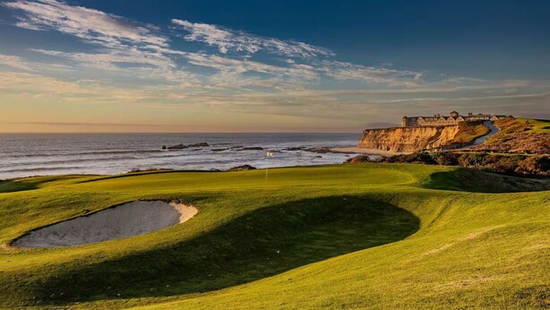 A coastal golf course with a large bunker, a flagstick, and a cliffside building overlooking the ocean. - Spacious 4300 sq ft Bay Escape – On Golf Course & Near to Beach and Trials (Half Moon Bay)