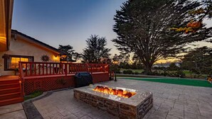 A patio with a fire pit, a red deck, and a lawn. - Spacious 4300 sq ft Bay Escape – On Golf Course & Near to Beach and Trials (Half Moon Bay)
